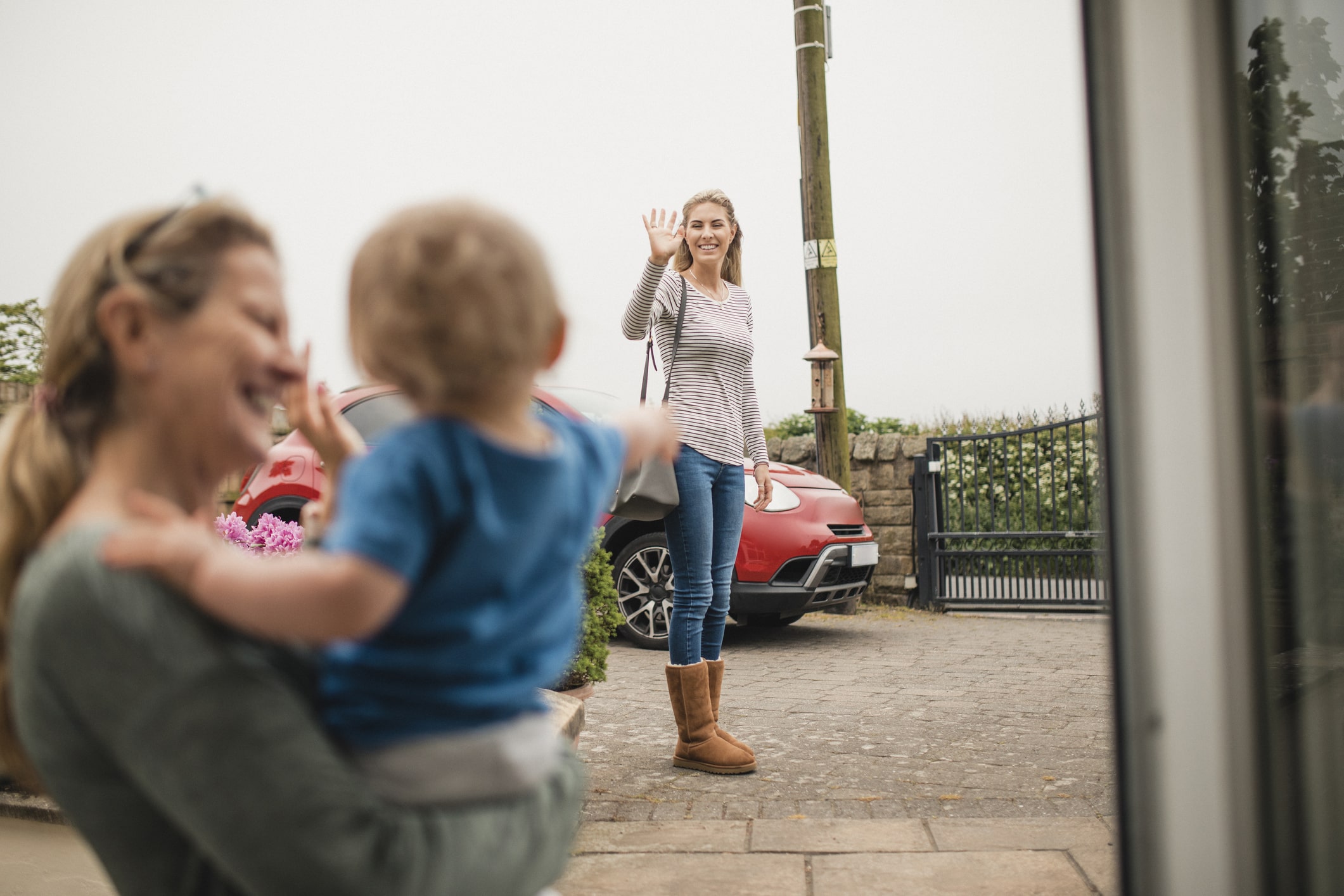 Woman waving goodbye to her child and babysitter